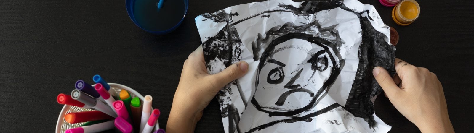 A child’s drawing painted entirely in black, viewed from above, representing childhood depression, emotional distress, and mental health challenges. Concept of autism, art therapy, psychological