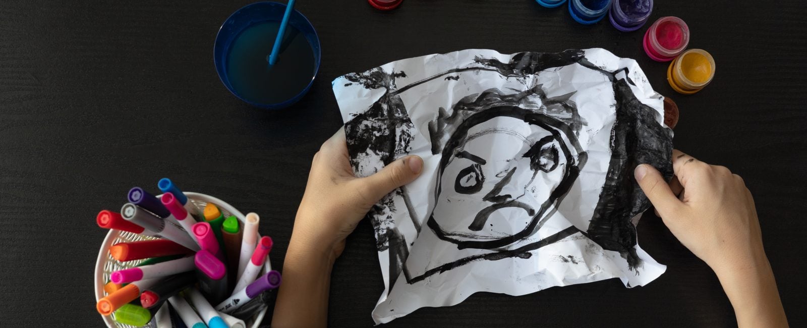 A child’s drawing painted entirely in black, viewed from above, representing childhood depression, emotional distress, and mental health challenges. Concept of autism, art therapy, psychological