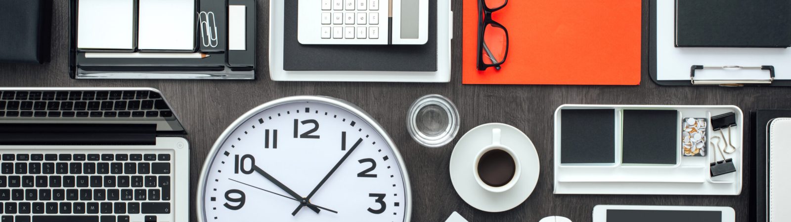 Corporate business desktop with laptop, office accessories and a clock: business productivity and deadlines concept