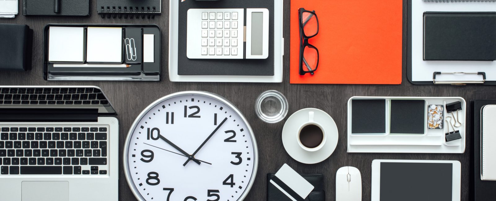 Corporate business desktop with laptop, office accessories and a clock: business productivity and deadlines concept
