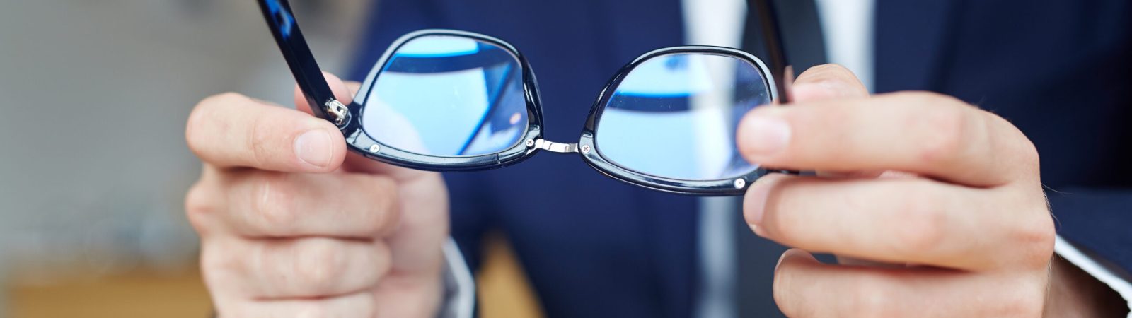 Human hands holding eyeglasses over touchpad