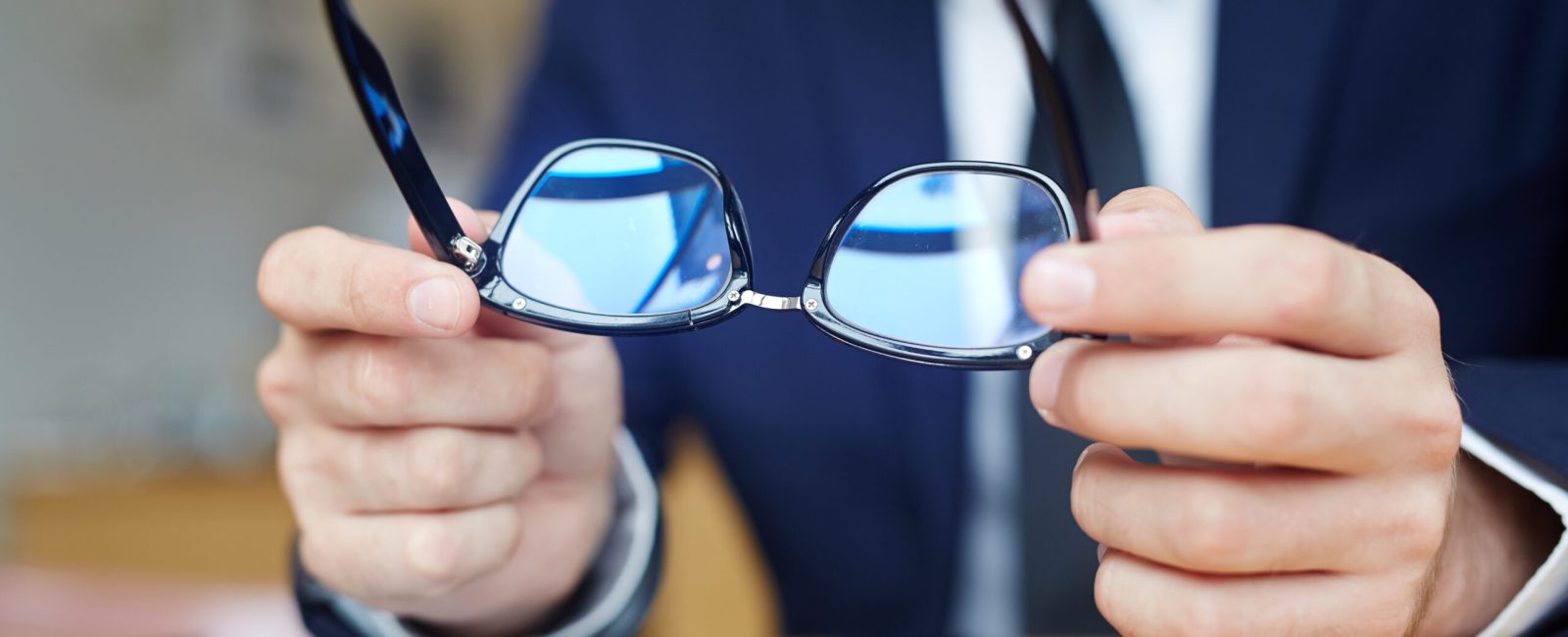 Human hands holding eyeglasses over touchpad