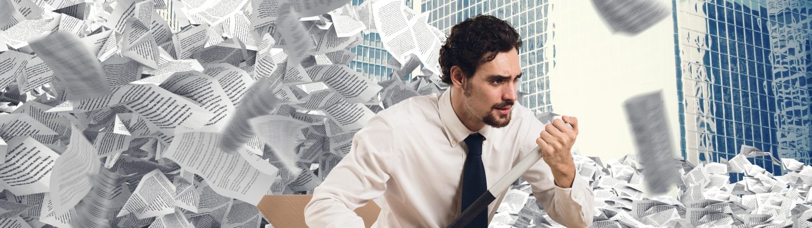Man in the middle of a sea of paper with a cardboard boat to get rid of