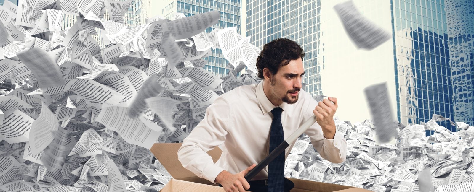 Man in the middle of a sea of paper with a cardboard boat to get rid of