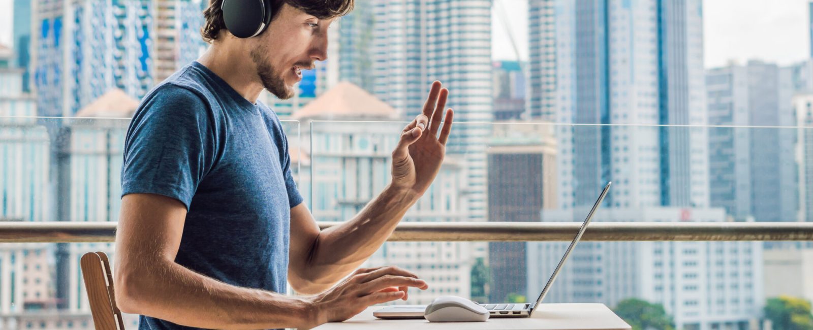 Young man teaches a foreign language or learns a foreign language on the Internet on her balcony against the backdrop of a big city. Online language school lifestyle. BANNER, long format
