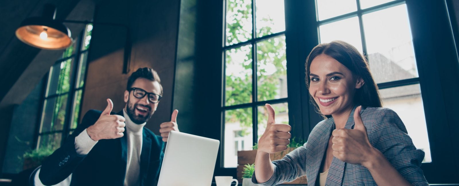 Low angle view of two cheerful intelligent modern professional stylish classic elegant people, managers, nice half-turned lady and bearded man showing thumbs up at industrial workplace, station