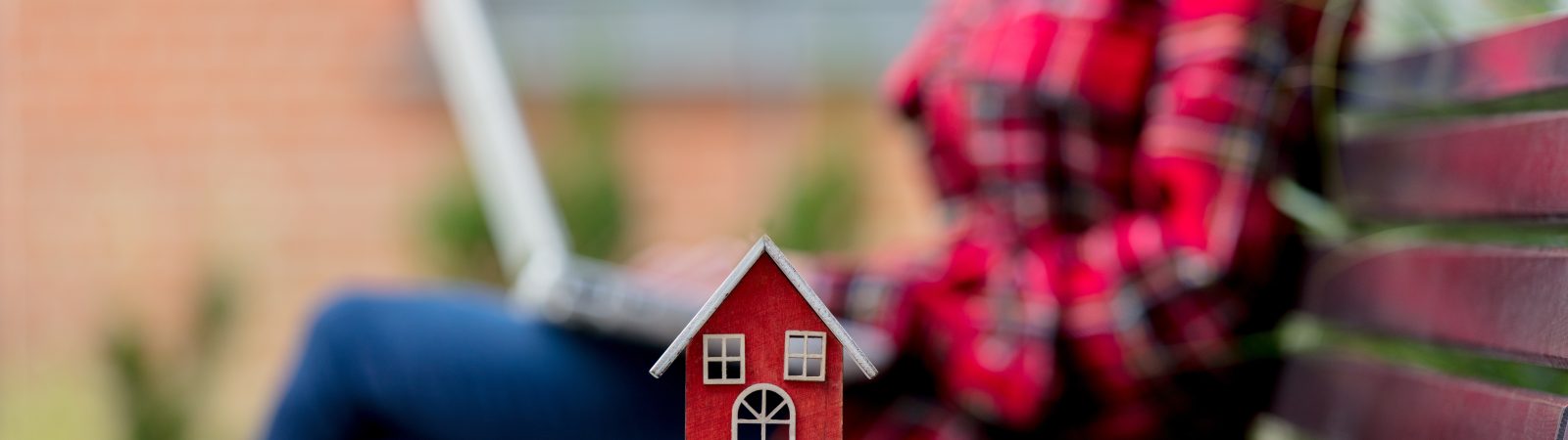 toy house on bench and girl with laptop computer on background