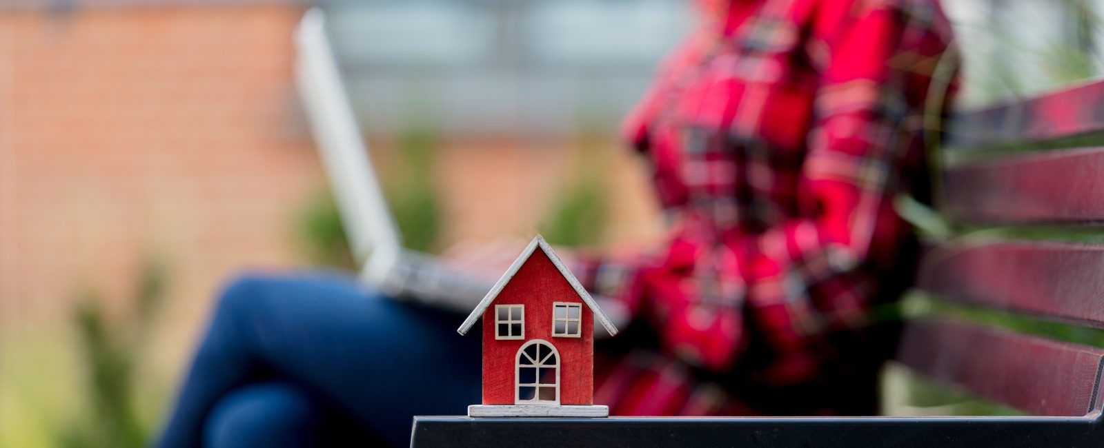 toy house on bench and girl with laptop computer on background