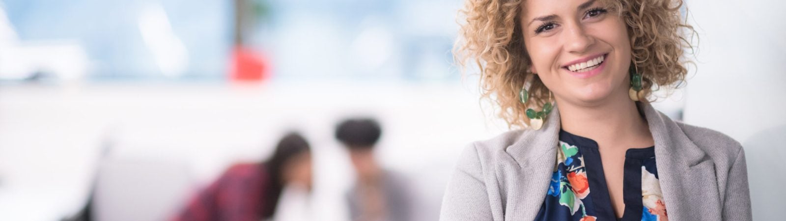 Portrait of successful female software developer with a curly hairstyle at modern startup office