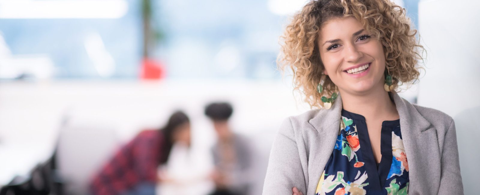 Portrait of successful female software developer with a curly hairstyle at modern startup office