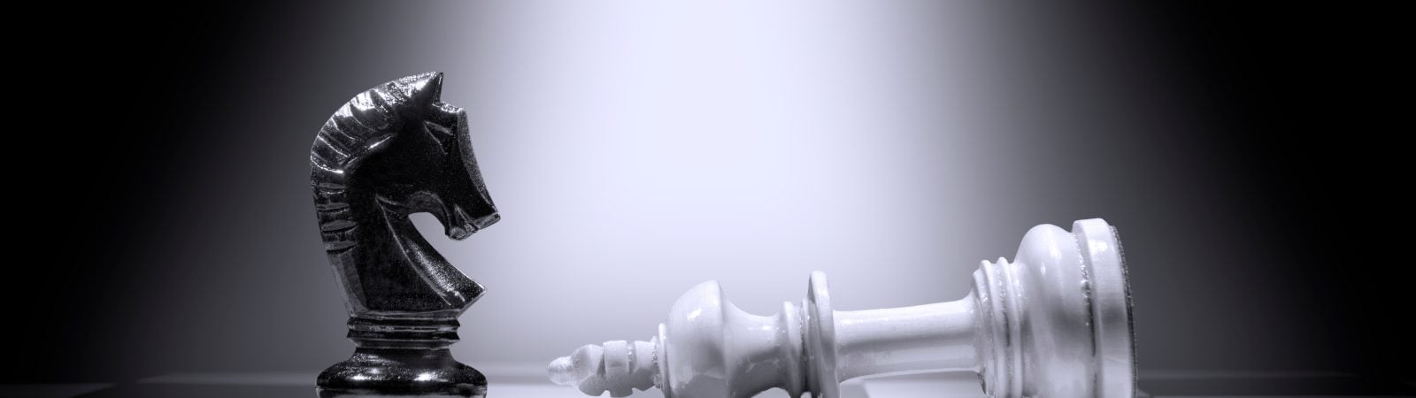 White king chess piece defeating by black knight chess piece on the chessboard