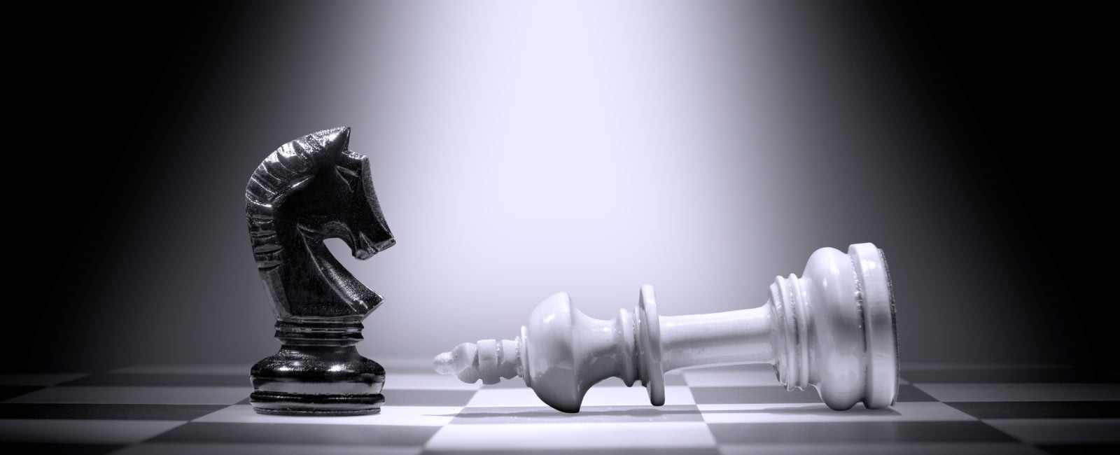 White king chess piece defeating by black knight chess piece on the chessboard