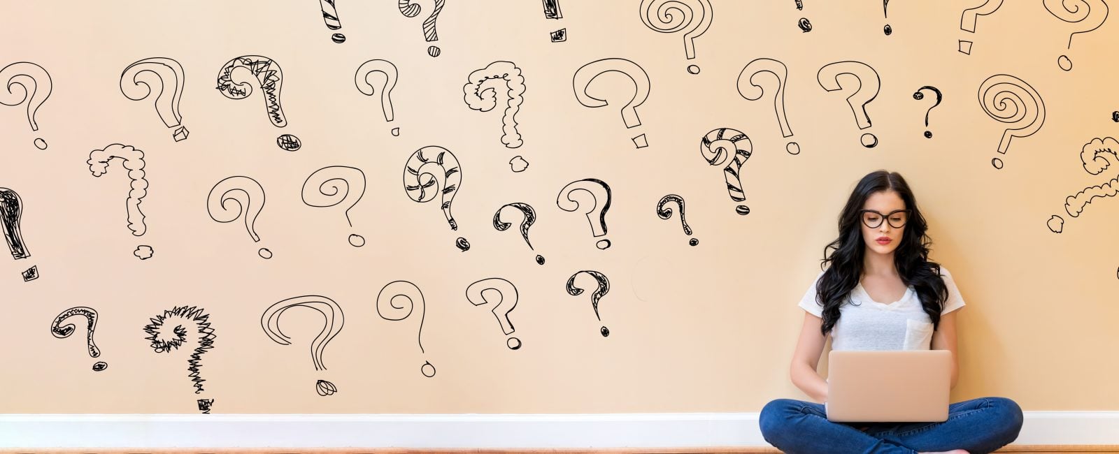 Small question marks with young woman using a laptop computer