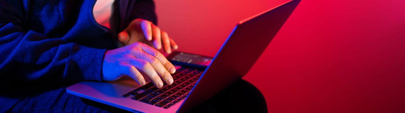 Young man with laptop. Red and blue neon light