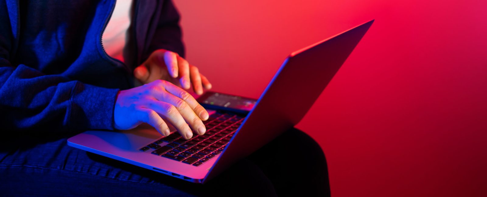 Young man with laptop. Red and blue neon light