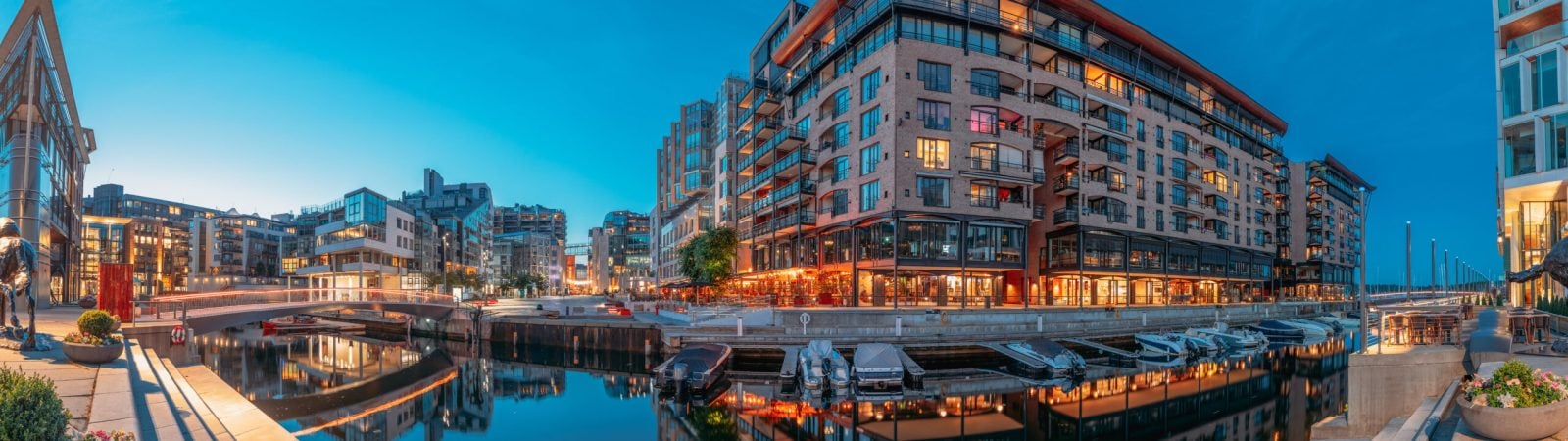 Oslo, Norway. Night Embankment And Residential Multi-storey Houses In Aker Brygge District. Summer Evening. Residential Area Reflected In Waters. Famous And Popular Place. Panorama, Panoramic View