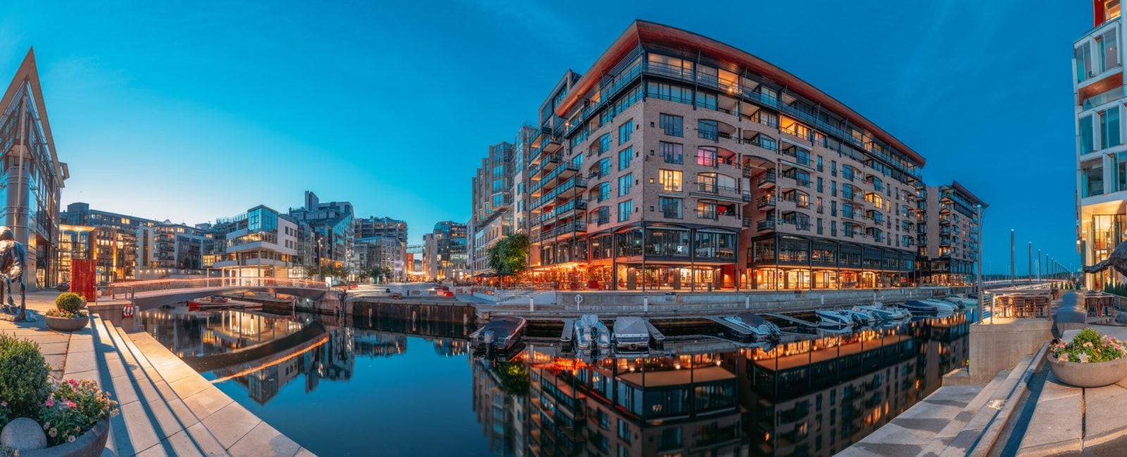 Oslo, Norway. Night Embankment And Residential Multi-storey Houses In Aker Brygge District. Summer Evening. Residential Area Reflected In Waters. Famous And Popular Place. Panorama, Panoramic View