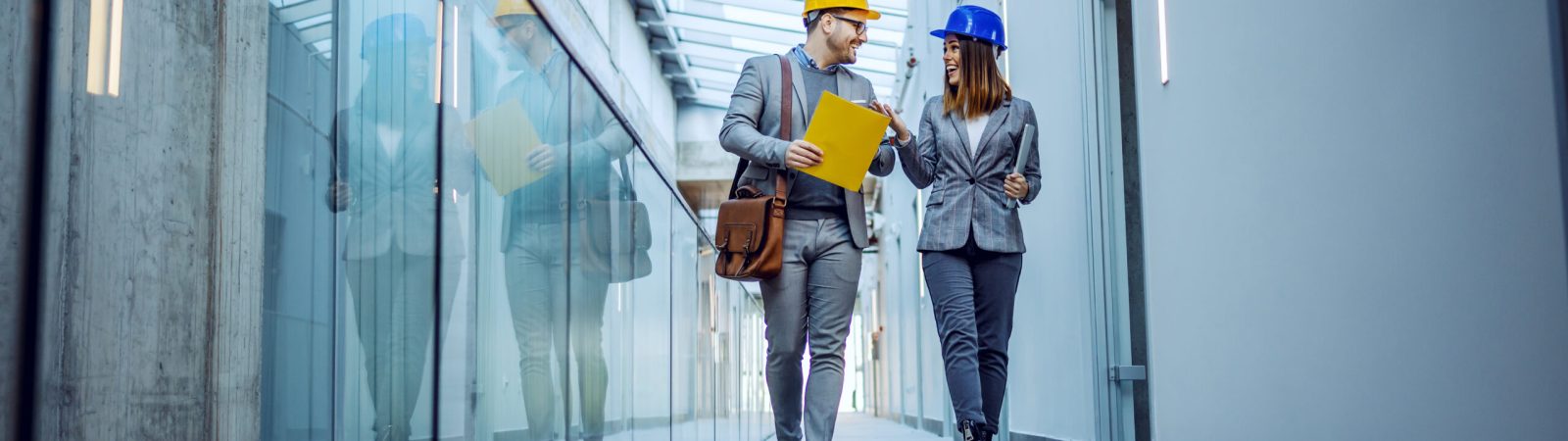 Two positive hardworking architects walking in hall of old building and talking about their plan to rebuild it into business center.