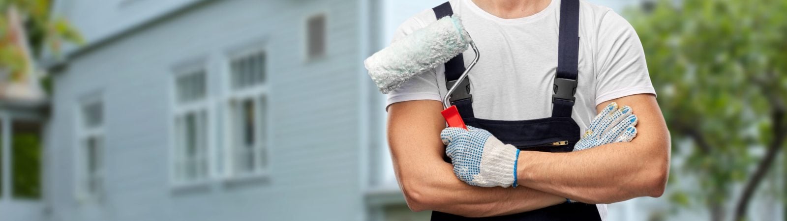 repair, construction and building - close up of painter or builder with paint roller over living house on background