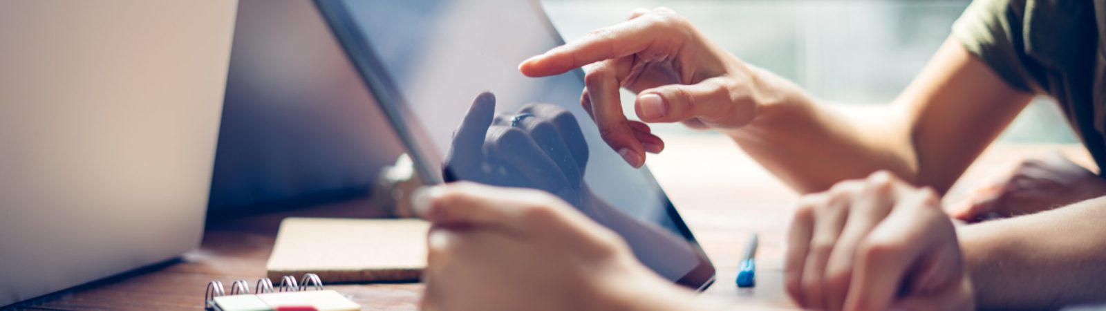 Group of young people working together. Creative business people in modern office. Hipster team in coworking. Freelancers at work. Close-up of female hands with digital tablet.