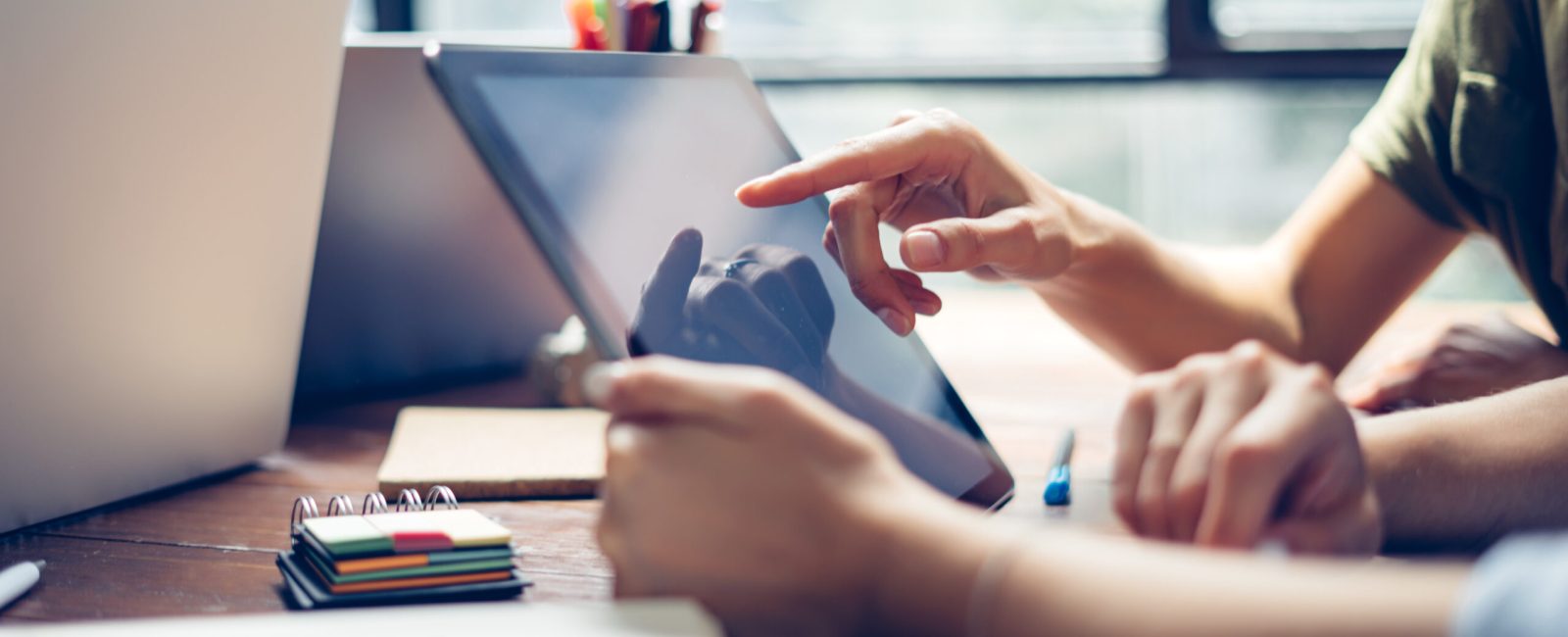 Group of young people working together. Creative business people in modern office. Hipster team in coworking. Freelancers at work. Close-up of female hands with digital tablet.