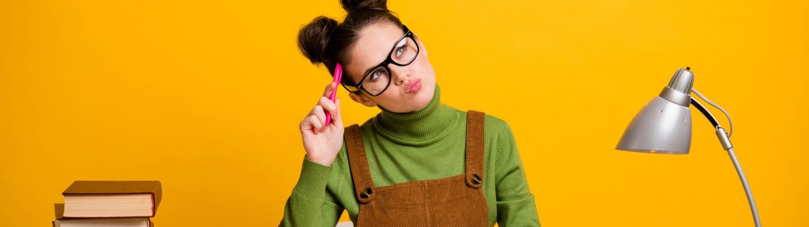 Photo of minded smart high school girl sit table prepare exam report think thoughts look copyspace pen touch forehead wear green sweater, isolated over bright shine color background