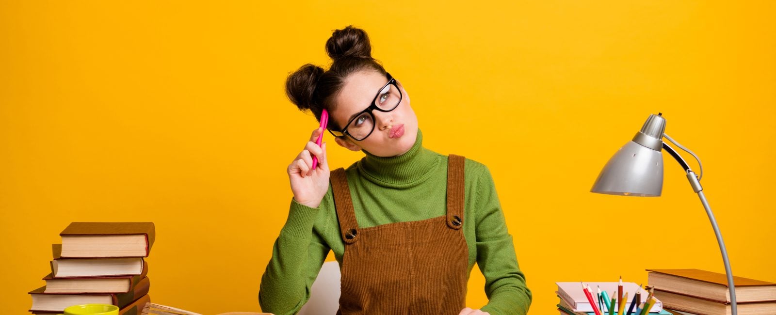 Photo of minded smart high school girl sit table prepare exam report think thoughts look copyspace pen touch forehead wear green sweater, isolated over bright shine color background