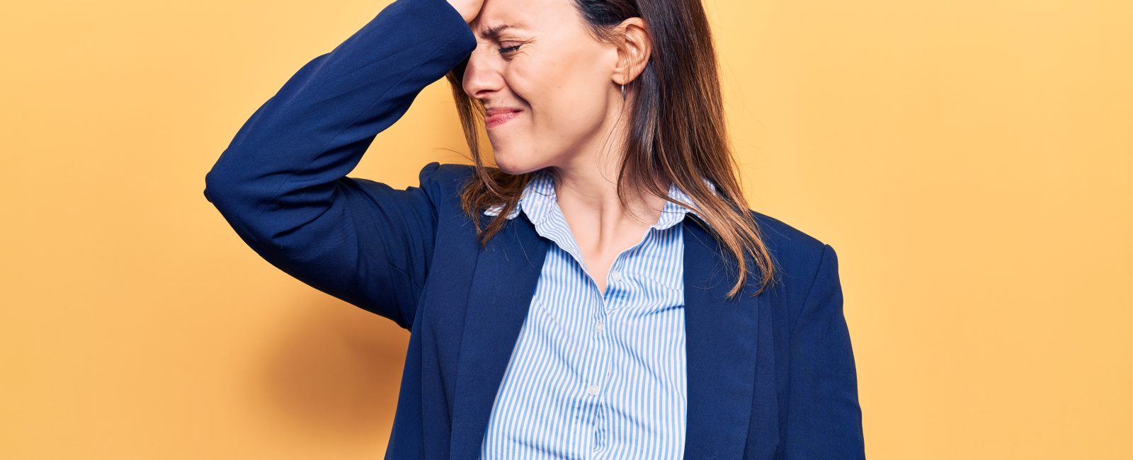Young beautiful woman wearing business clothes surprised with hand on head for mistake, remember error. forgot, bad memory concept.