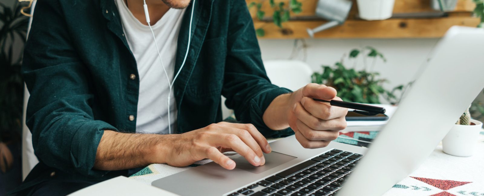 Handsome man with laptop working remotely from home, making video call. Freelancer at remote work. Cozy workplace