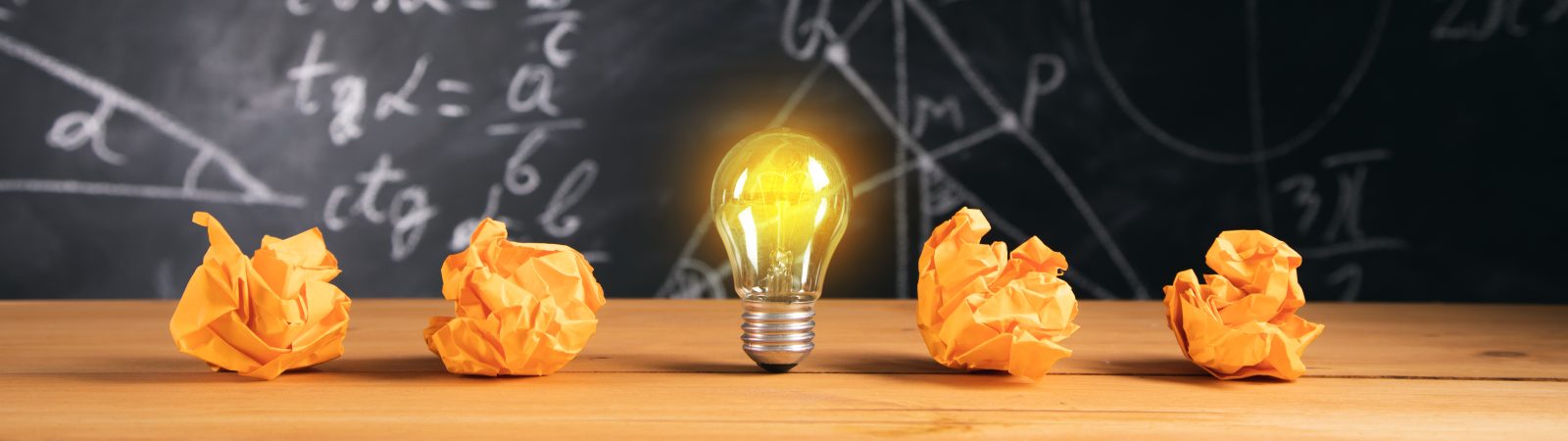 New idea, light bulb with papers on blackboard background