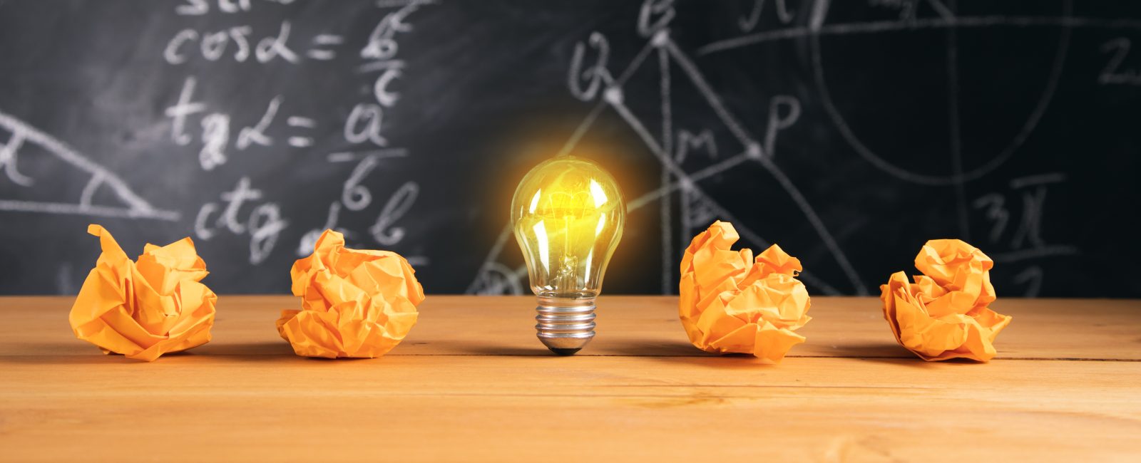 New idea, light bulb with papers on blackboard background