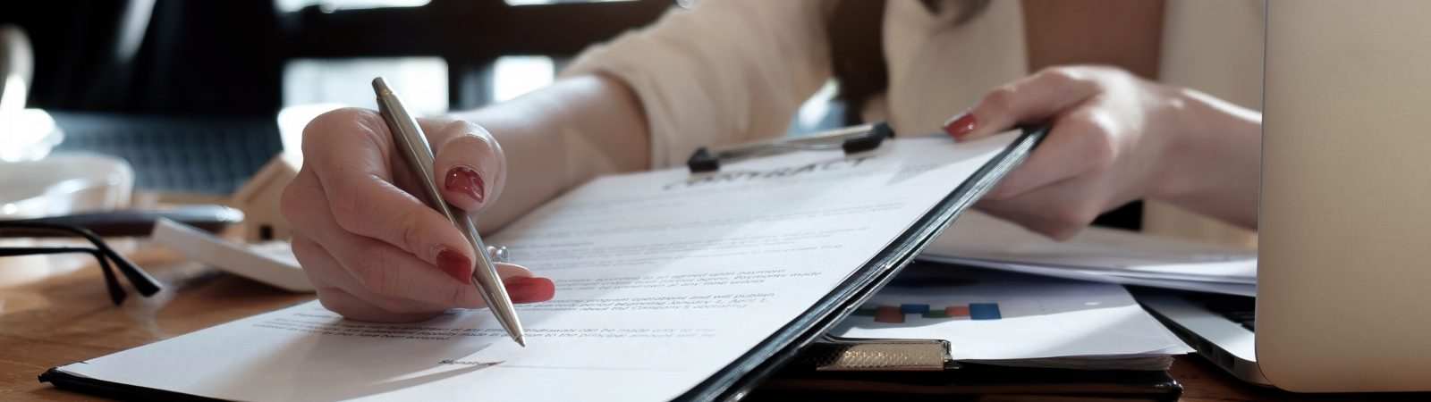 real estate agent assisting client to sign contract paper at desk with house model.