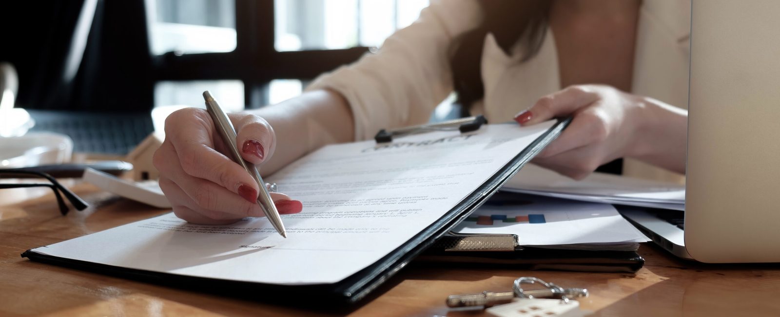 real estate agent assisting client to sign contract paper at desk with house model.