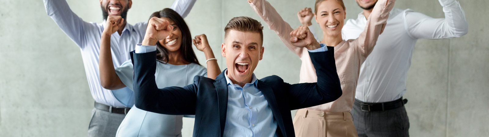 Group Of Multiethnic Business People With Male Leader Celebrating Success With Raised Fists, Happy Team Of Coworkers Exclaiming With Excitement, Emotionally Reacting To Company Achievement