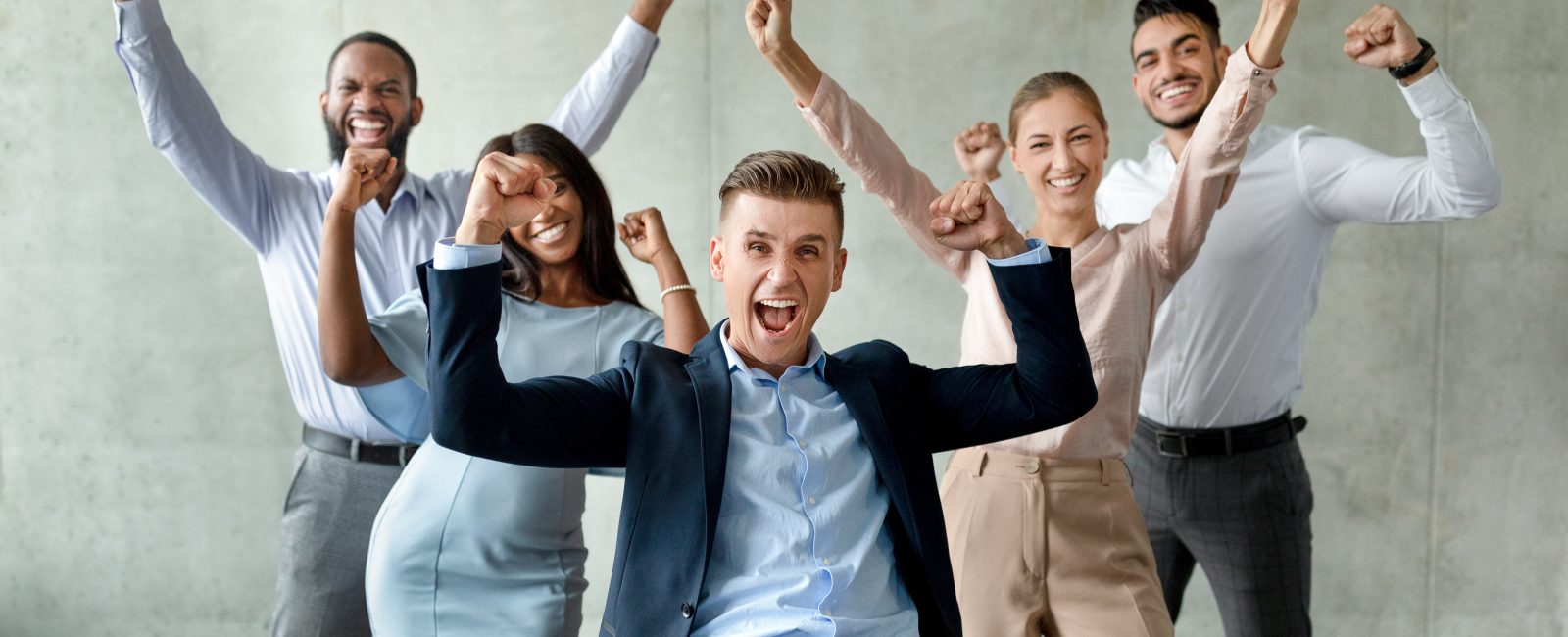 Group Of Multiethnic Business People With Male Leader Celebrating Success With Raised Fists, Happy Team Of Coworkers Exclaiming With Excitement, Emotionally Reacting To Company Achievement