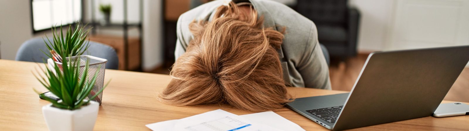 Middle age businesswoman overworked with head on desk at the office.