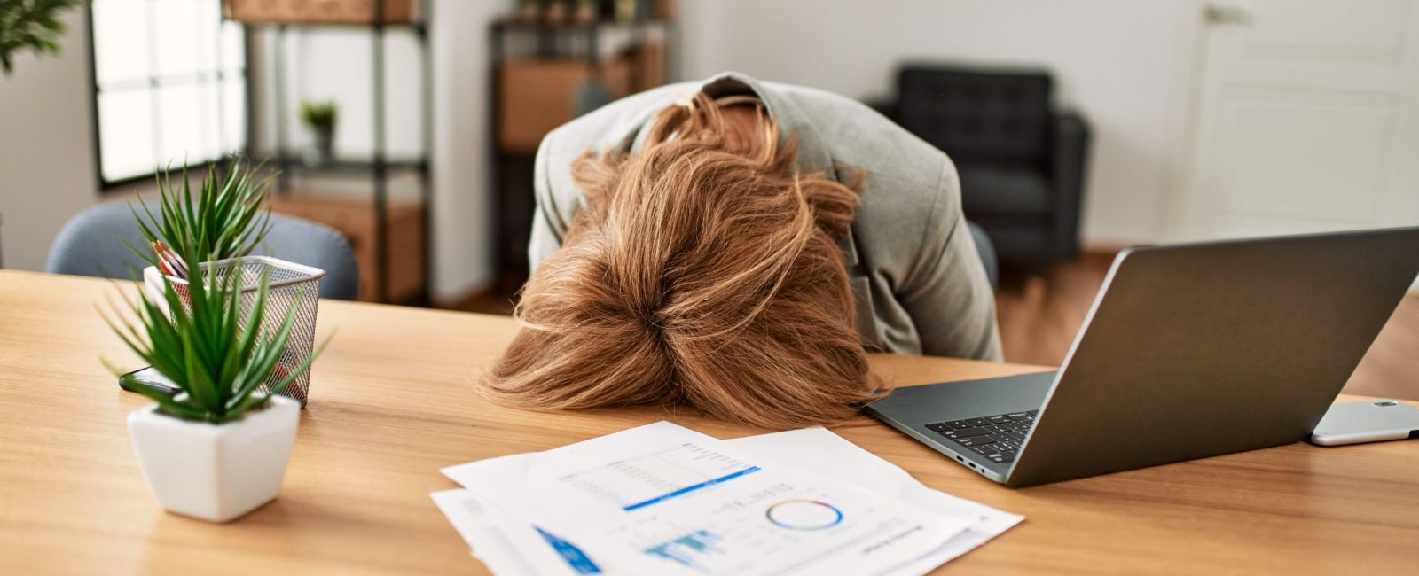 Middle age businesswoman overworked with head on desk at the office.