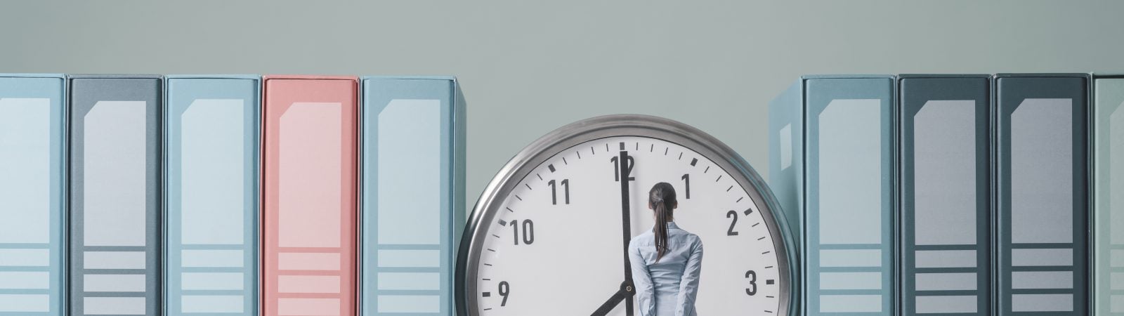 Businesswoman holding her briefcase and checking the time on a huge clock, she is standing and waiting
