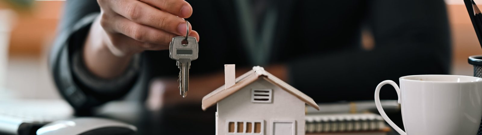 Cropped shot real estate agent  holding house key. Insurance or loan real estate concept.