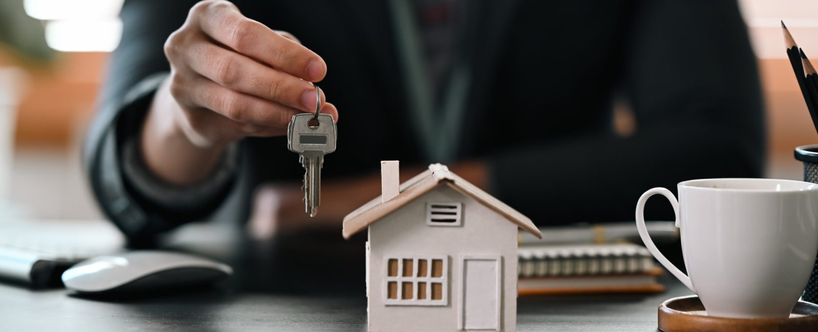 Cropped shot real estate agent  holding house key. Insurance or loan real estate concept.