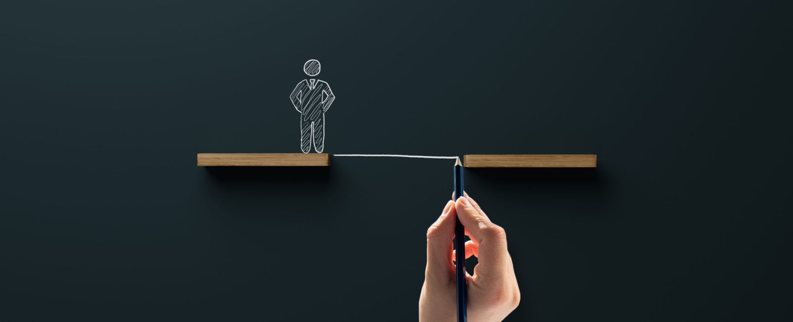 Wooden blocks and a drawn figure with a chasm, the hand draws a bridge, a passage. Concept of help in business and dealing with problems.