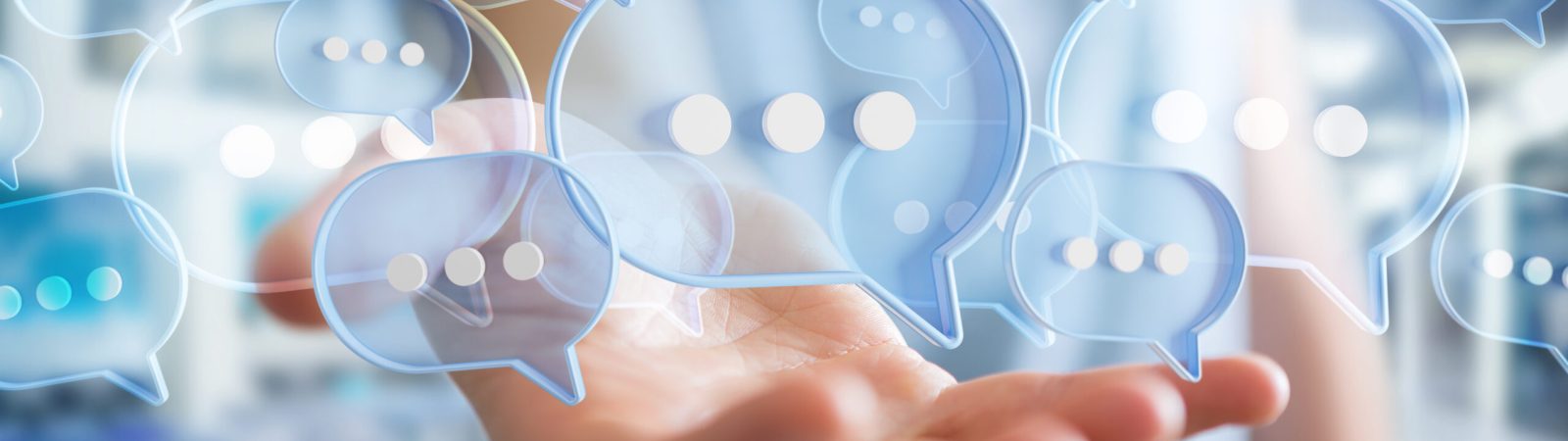 Businessman using digital blue speech bubbles talk icons. Minimal conversation or social media messages floating over user hand. 3D rendering