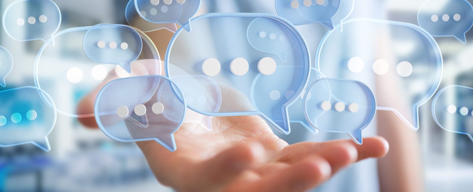 Businessman using digital blue speech bubbles talk icons. Minimal conversation or social media messages floating over user hand. 3D rendering