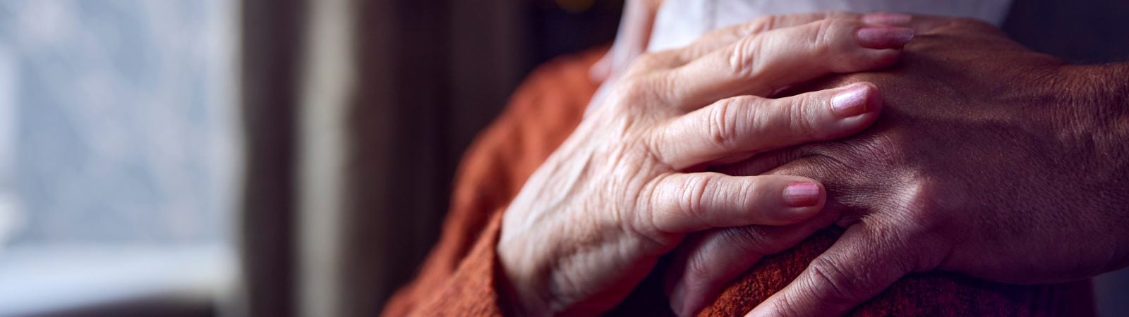 Close Up Of Senior Couple At Home With Man Putting Reassuring Hand On Woman's Shoulder