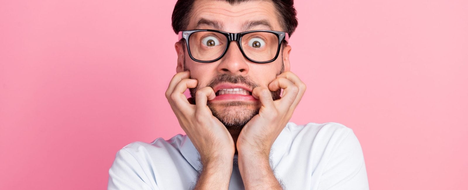 Closeup photo of young funnny handsome attractive bearded man bite fingers nails nervous face wear glasses deadline work manager isolated on pink color background.
