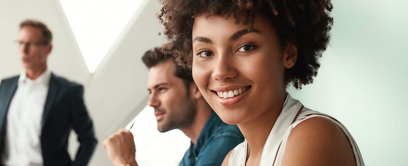 Cheerful businesswoman. Young afro american woman is looking at camera and smiling while her boss standing near whiteboard and discussing something with team. Teamwork. Meeting