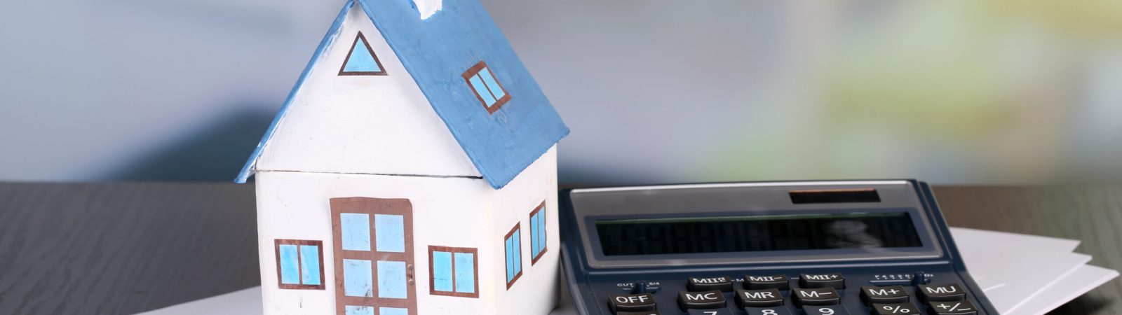 Toy house and calculator on table close-up
