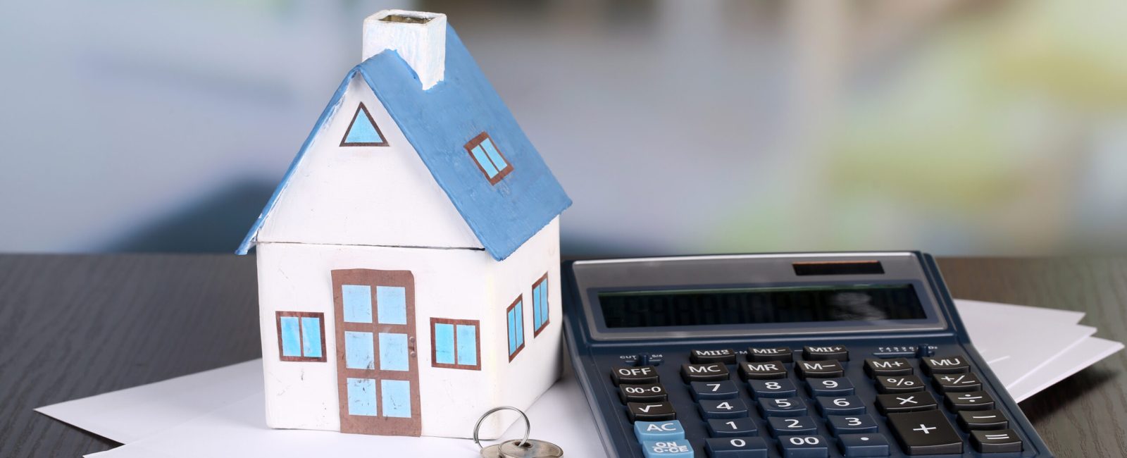 Toy house and calculator on table close-up